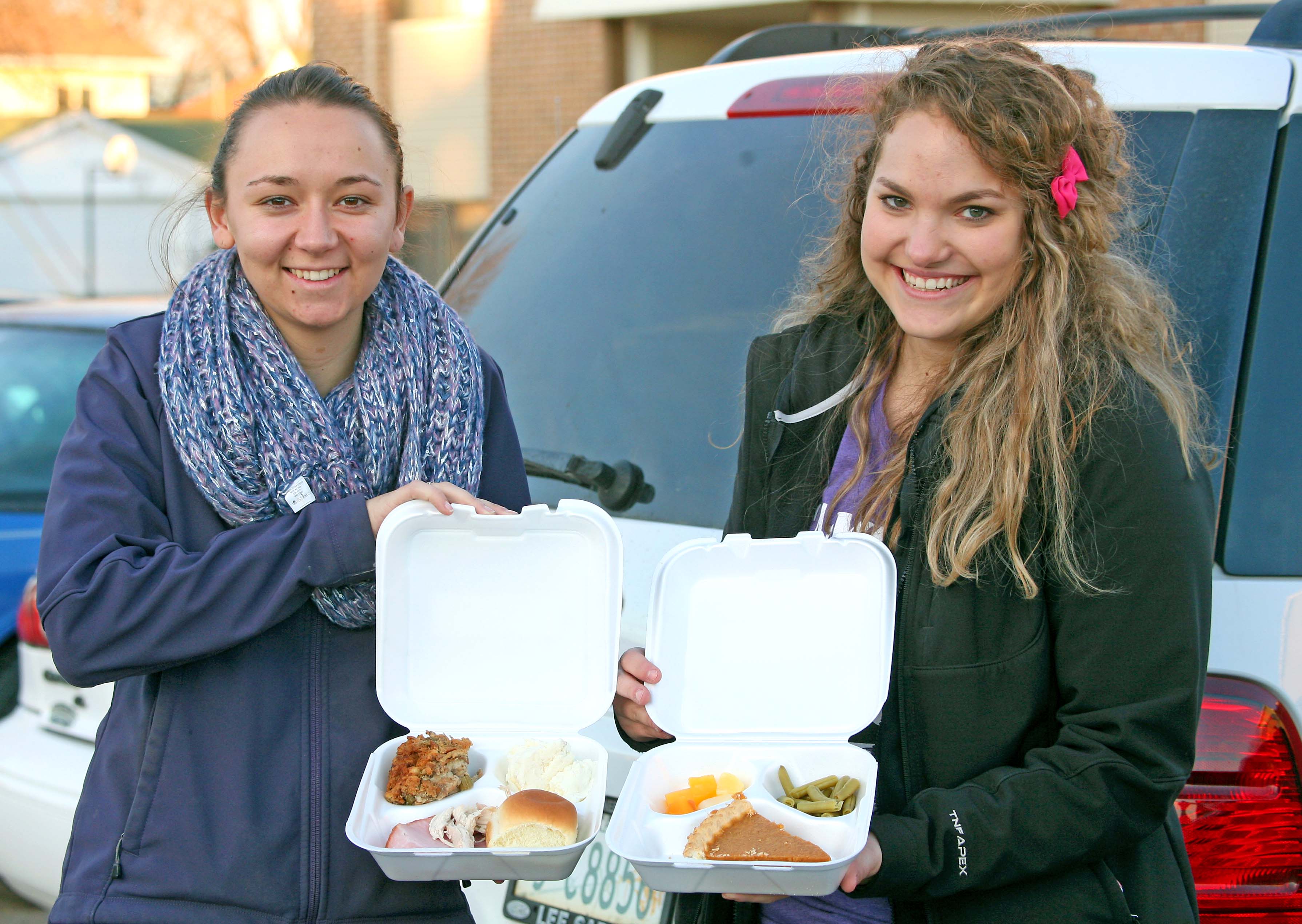 UNK senior biology majors Whitney Nelson, left, and Kelsie Musil deliver a Thanksgiving meal to a Kearney resident Monday during UNK Campus Kitchen's TurkeyPalooza. During TurkeyPalooza, student volunteers delivered nearly 100 meals to residents in need. (Photo by Sara Giboney/UNK News)