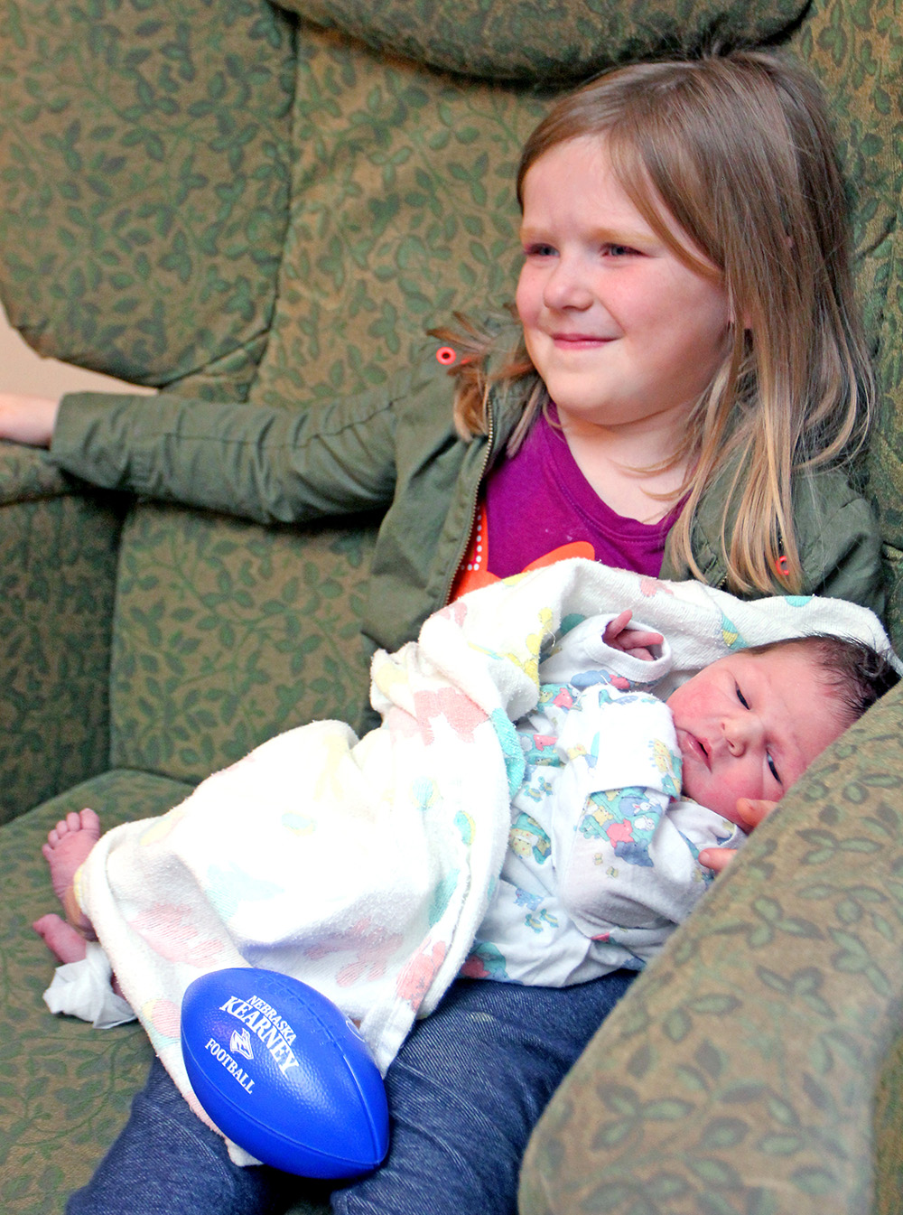 TayLee Donahoo holds her newborn brother, Trysten, after receiving a football from UNK players Monday. TayLee and Trysten are the children of Alysha Donahoo of Kearney.