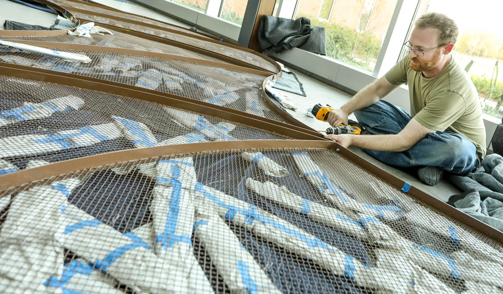 Corey Kapellas of San Francisco assembles new artwork Tuesday that is being hung this week inside the Health Science Education Complex at the University of Nebraska at Kearney. The piece of art, titled “River At Dawn,” is a suspended aluminum sculpture that weighs 250 pounds and measures 50 feet long. The sculpture was created by San Francisco artist Daniel Goldstein and was inspired by the Platte River. The project – a partnership between UNK, University of Nebraska Medical Center and Nebraska Arts Council – is funded by the 1% For Art program that places art in Nebraska’s state buildings, colleges and University of Nebraska system. (Photo by Corbey R. Dorsey/UNK Communications) 