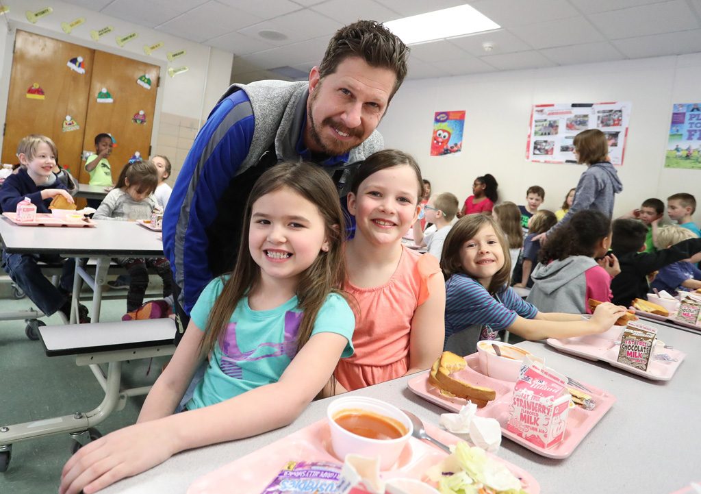 Principal Mark Johnson interacts with Bryant Elementary students during their lunch break. Johnson and Sam Stecher, another UNK graduate and superintendent at East Butler Public Schools, are connecting with other educators through their Mission Monday curriculum and book “It Happens in the Hallway.” (Photo by Corbey R. Dorsey/UNK Communications)