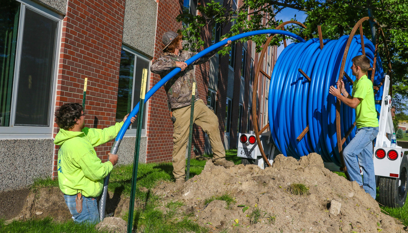 Myers Construction of Broken Bow workers, from left, Jake McCormick, Slade Russell and Collin Hoffman roll out tubing that is part of new fiber optic ring installation that will improve information technology services at UNK. (Photo by Corbey R. Dorsey/UNK Communications)