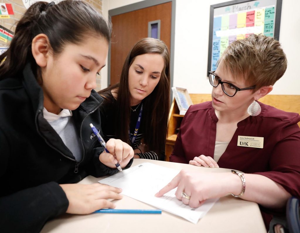 From left, Avery Lopez, a seventh-grader at Horizon Middle School in Kearney, receives help on a math assignment from UNK junior Kaylea Watson, middle, and associate math and statistics professor Amy Nebesniak, right, during a recent study hall period. Students from the Math 430 class taught by Nebesniak are serving as tutors at the middle school this semester. (Photo by Corbey R. Dorsey, UNK Communications)