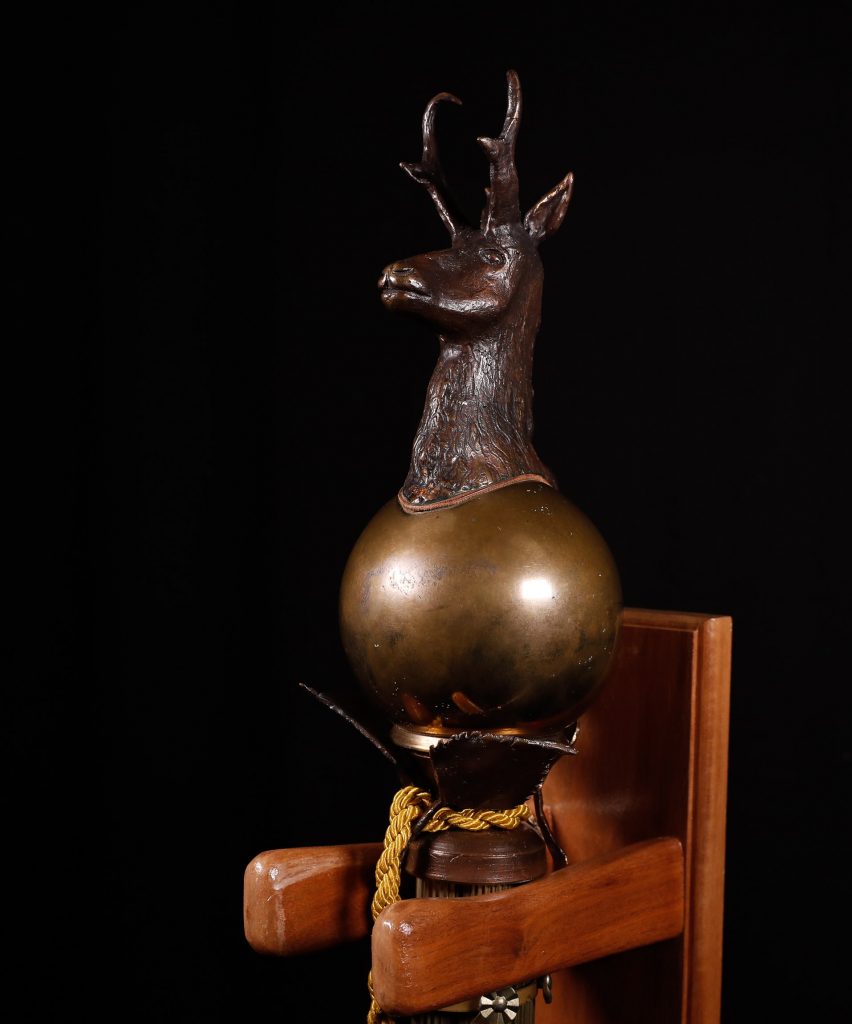 Raymond Schultze, an assistant art professor at UNK from 1965 to 2000, designed and constructed the university’s ceremonial mace. It is topped with a pronghorn antelope head – the school’s mascot – and draped in blue and gold tassels. (Photo by Corbey R. Dorsey, UNK Communications)