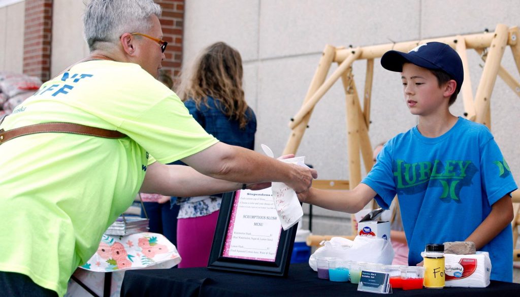 Ten-year-old Koji Kitabatake of Kearney, right, serves a slush to a customer Friday evening during the Biz Kidz Camp product showcase at the Kearney Hy-Vee. (Photo by Tyler Ellyson, UNK Communications)