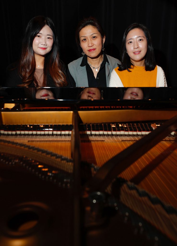 UNK piano instructor Jayoung Hong, center, says it’s a privilege to teach students Seulji Kim, left, and Seungwon Lee. “They are exceptional talents and musicians,” Hong said. (Photo by Corbey R. Dorsey, UNK Communications