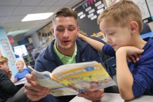 UNK wrestler Mike Lambert, a senior from Fremont, reads to Meadowlark Elementary School first-grader Barrett Hill during a recent visit. Members of the UNK wrestling team stop by the Kearney elementary school each week to read with students and participate in other fun activities. (Photo by Corbey R. Dorsey, UNK Communications)