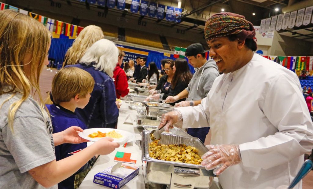 Jahad Al Bulushi, a UNK student from Oman, serves chicken kabuli to a line of hungry attendees at Sunday’s Scott D. Morris International Food and Cultural Festival. Dishes from nine countries were featured during the annual event at UNK’s Health and Sports Center. (Photo by Todd Gottula, UNK Communications)