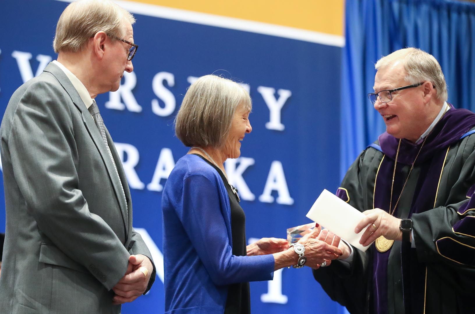 UNK Chancellor Doug Kristensen, right, presents the Ron and Carol Cope Cornerstone of Excellence Award to Jerry and Nancy Dulitz during Friday's spring commencement at the Health and Sports Center. (Photo by Corbey R. Dorsey, UNK Communications)