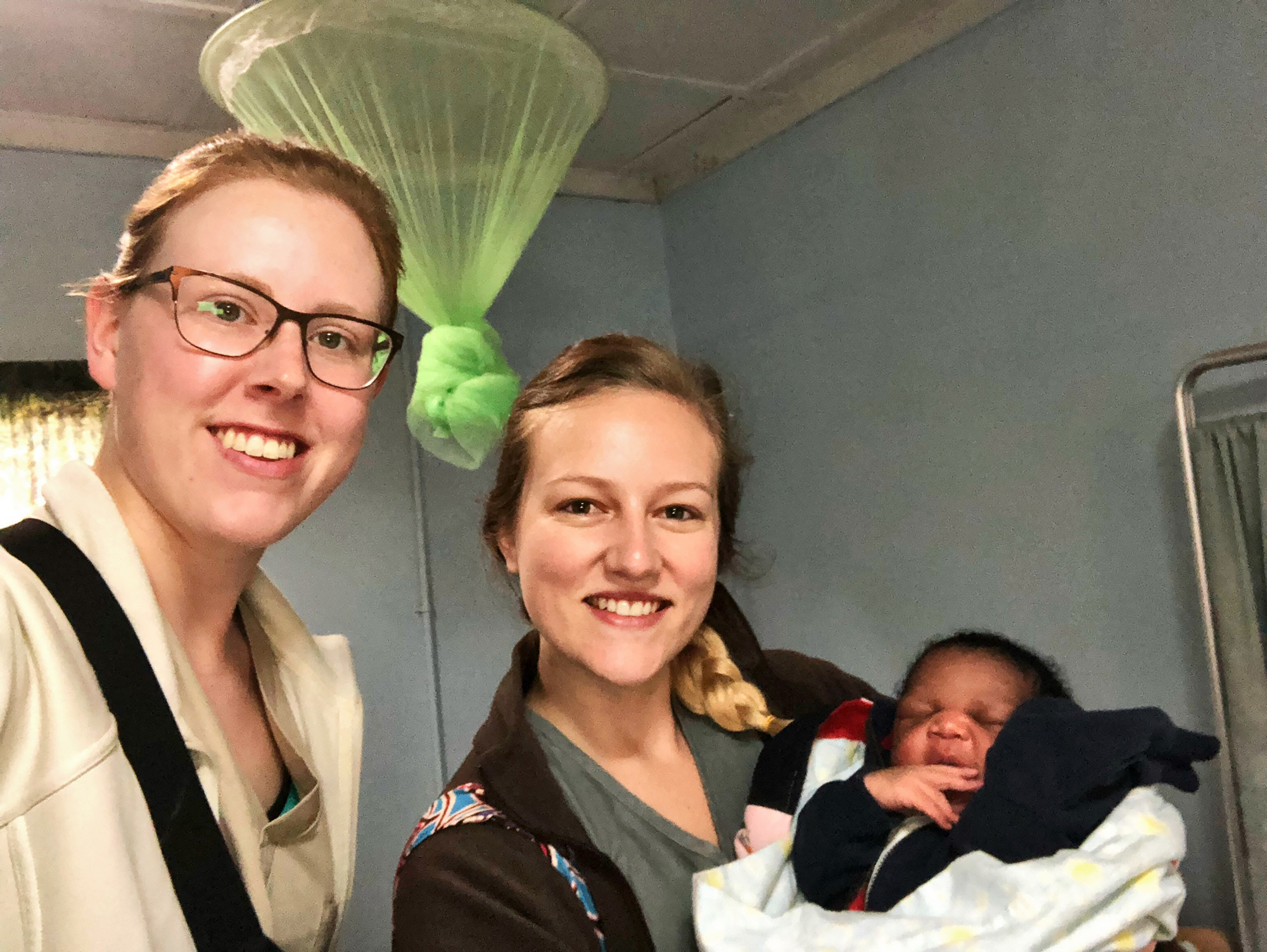 UNK student Michaela Walker, left, and UNK graduate Tessa Copp are pictured with a baby they helped deliver at the Chifundo Rural Health Center in Zambia. (Courtesy photo)