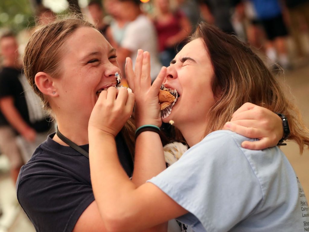 UNK freshmen Avril Jones, left, and Megan Kinzle celebrate with a cupcake fight Thursday evening after they were named the “default” winners of the eating contest during Destination Downtown. (Photo by Corbey R. Dorsey, UNK Communications)