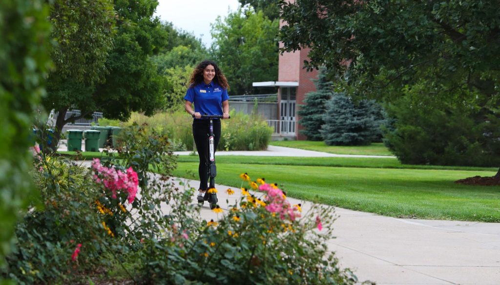 UNK student Catherine Arias Barrios rides one of nine electric scooters available for students, staff, faculty and visitors to rent and ride on campus.
