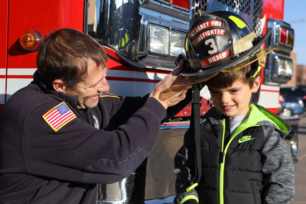 Bowen Wyant tries on a firefighting helmet with assistance from George Wiedel.