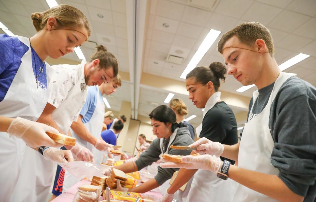 UNK student-athletes make peanut butter and jelly sandwiches Tuesday during a community service project on campus.