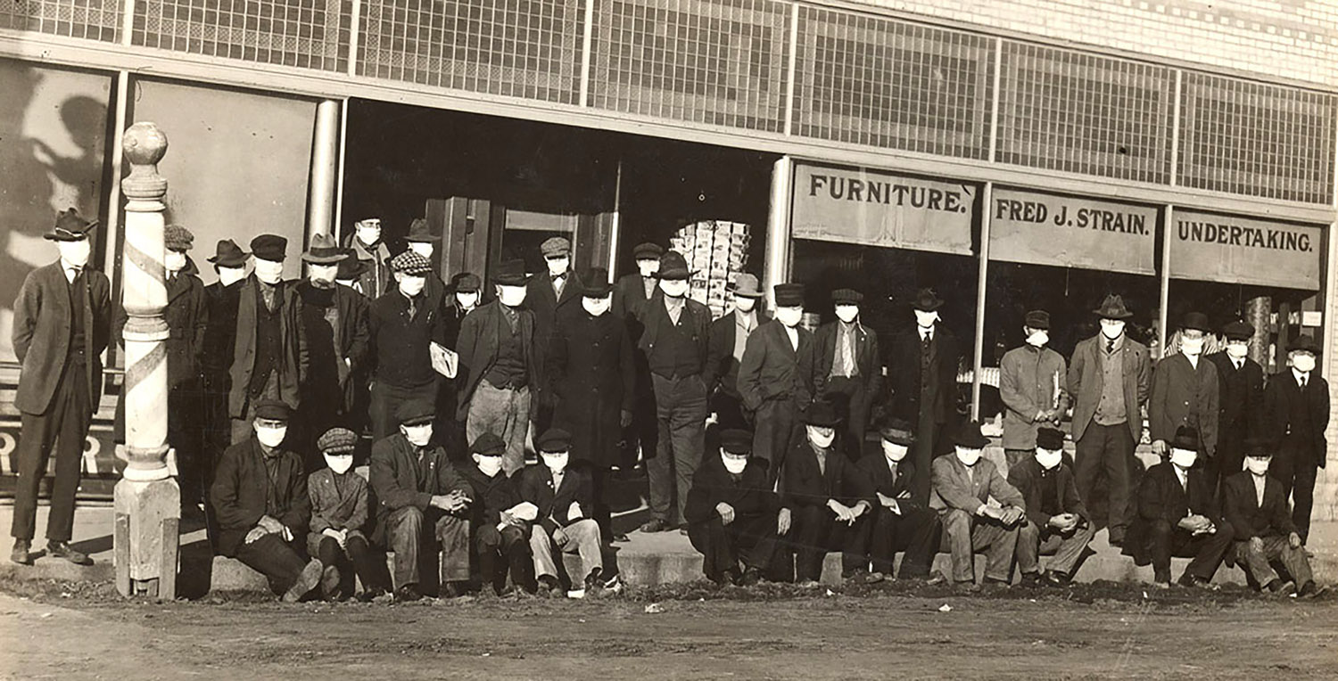 A group of men wearing protective face coverings are pictured in front of a Shelby business during the Spanish flu outbreak in December 1918. (Nebraska State Historical Society)