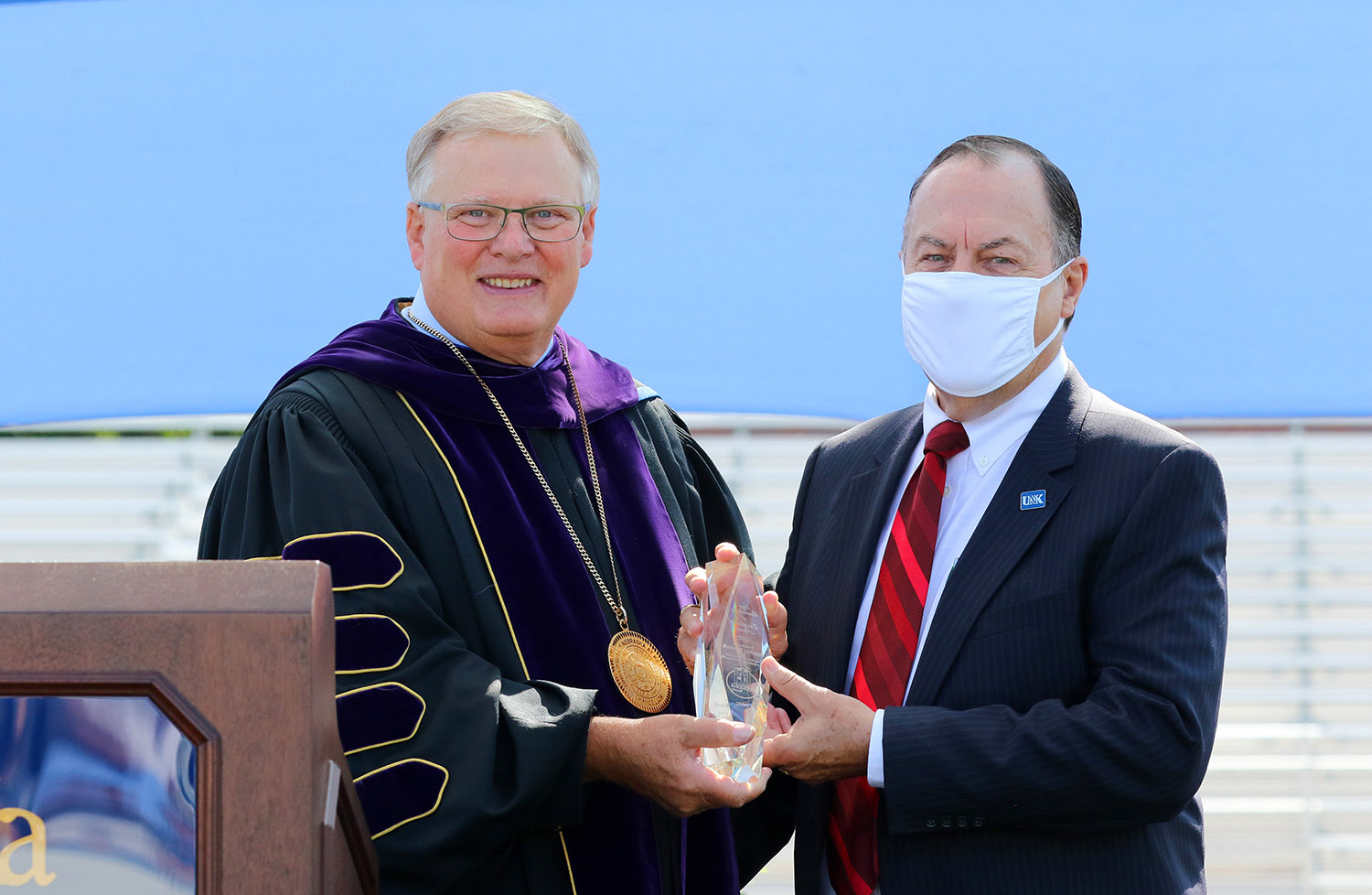 Brad Kernick, right, receives the Ron and Carol Cope Cornerstone of Excellence Award from UNK Chancellor Doug Kristensen during Friday’s commencement at Cope Stadium on campus. (Photo by Todd Gottula, UNK Communications)