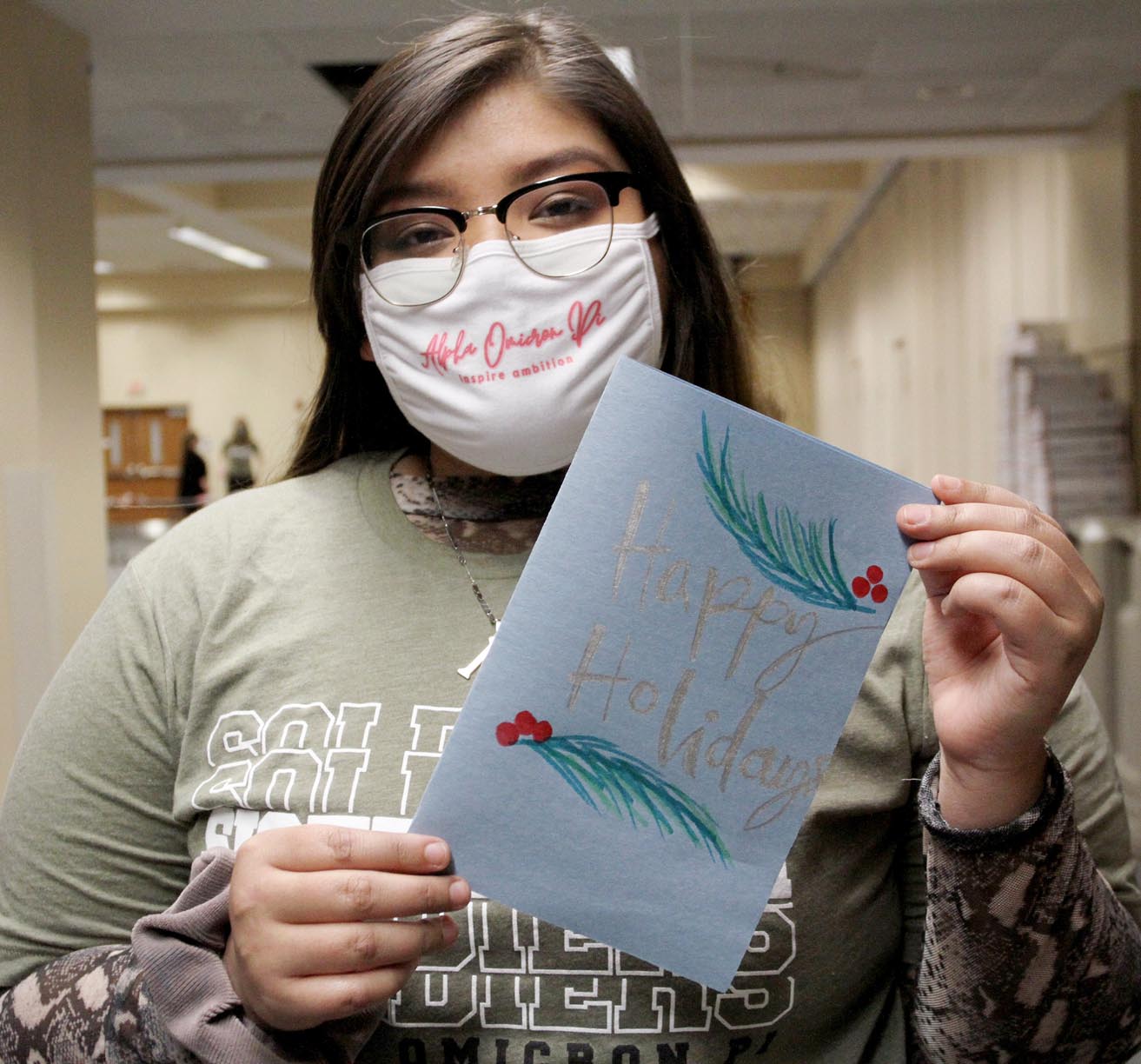 Alpha Omicron Pi member Emelin Ortega of Lexington is pictured with a holiday card she created for a U.S. military member.