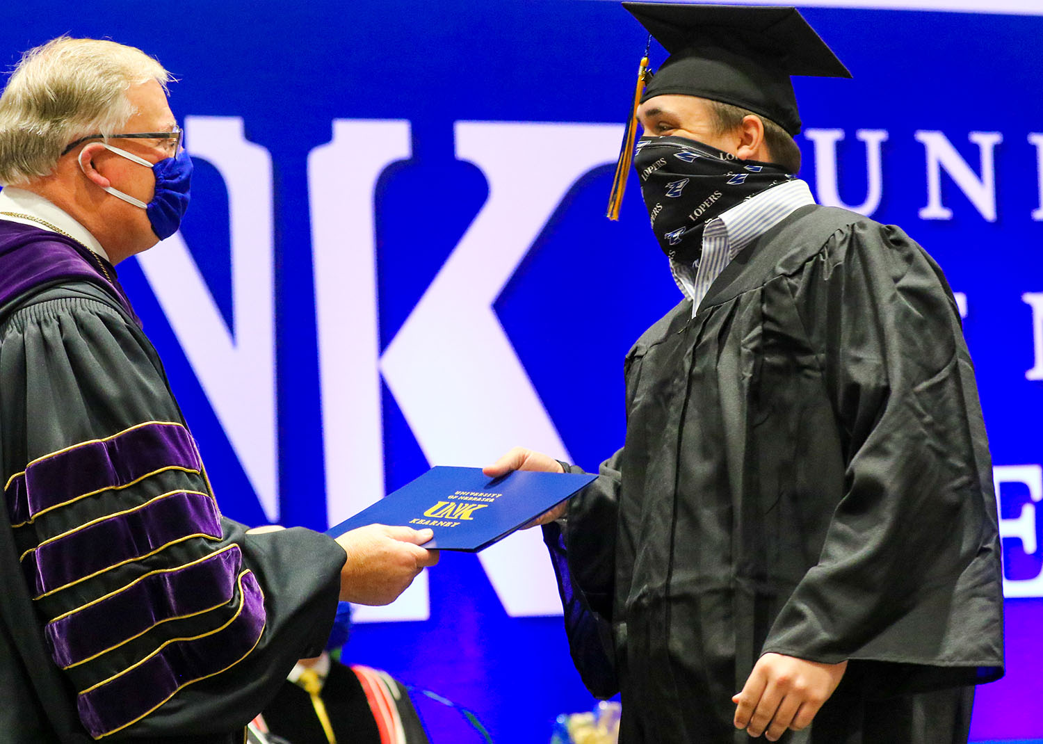 Logan Bunger of McCook, right, receives his degree from UNK Chancellor Doug Kristensen during Friday’s commencement ceremony. Bunger, who earned a bachelor’s degree in agribusiness, already accepted a job with Holdrege-based Nebraskaland Aviation.