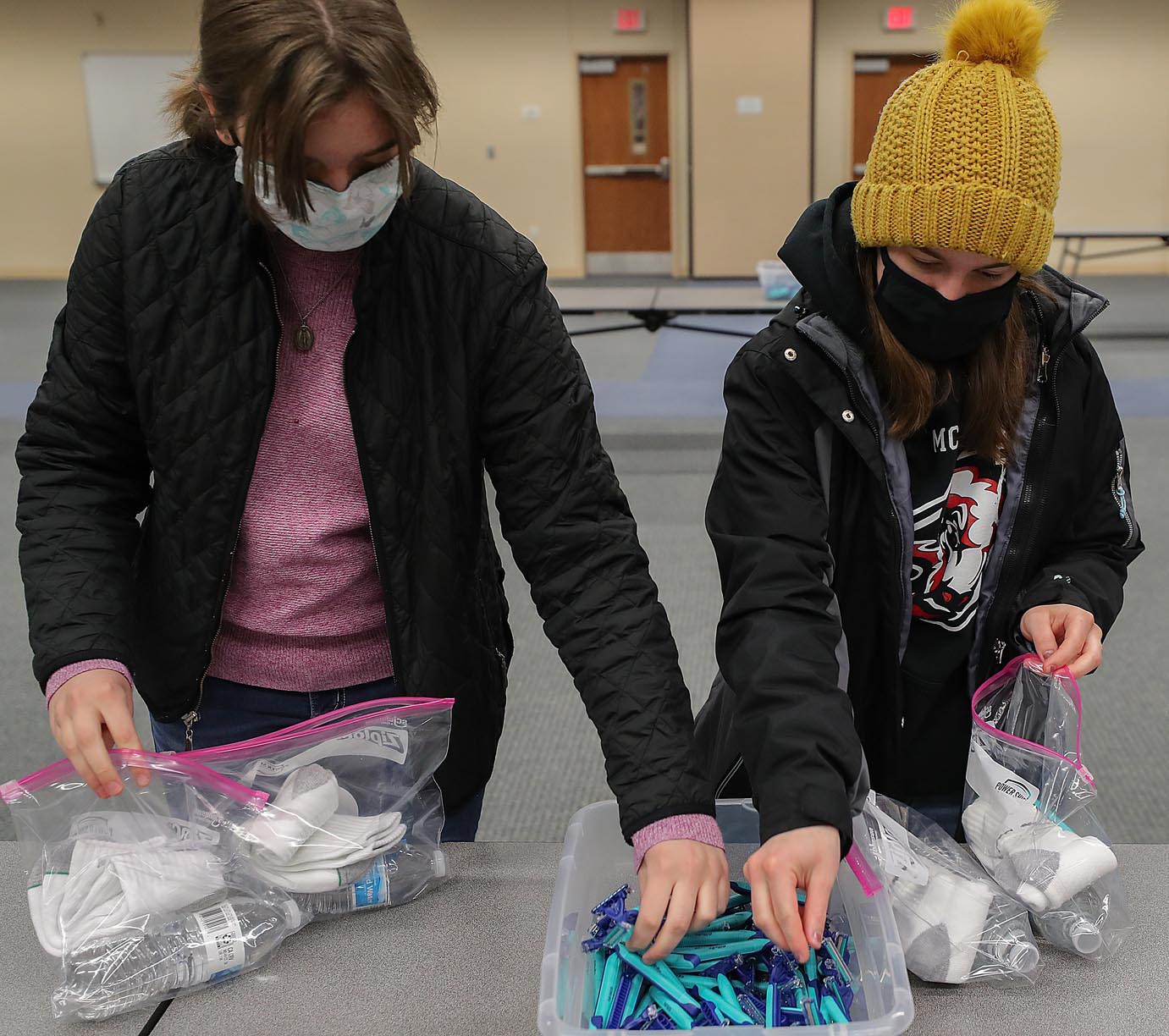 UNK freshmen Sylvia Dierking, left, and Jackie Hinze assemble care packages Friday during the MLK Day of Service. A total of 350 care packages containing bottled water, socks and a variety of hygiene products will be delivered to Crossroads Mission Avenue and Kearney Jubilee Center.