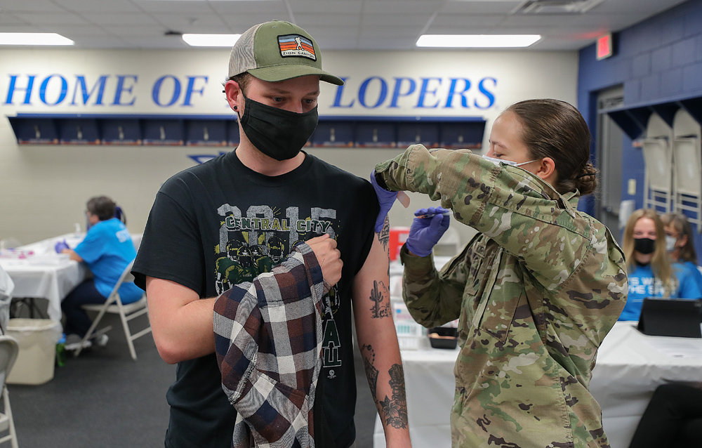 Nebraska Army National Guard member Jami Kirchner, right, gives UNK senior Jaden Powers his first dose of the COVID-19 vaccine Tuesday morning at UNK's Cope Stadium. (Photos by Erika Pritchard, UNK Communications)