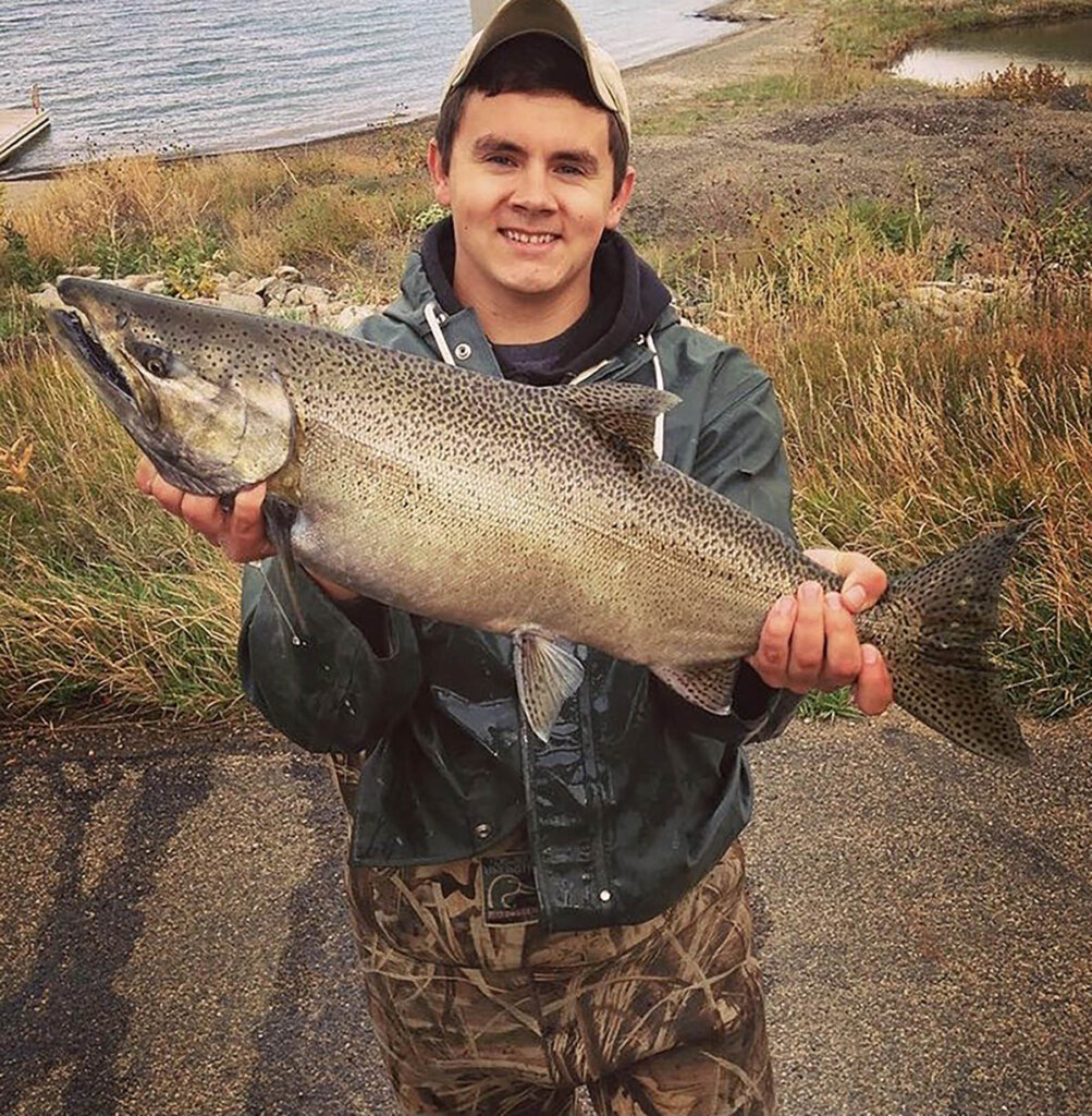 Dylan Gravenhof holds a Chinook salmon in fall 2018 while collecting eggs at Lake Oahe. (South Dakota Game, Fish and Parks)