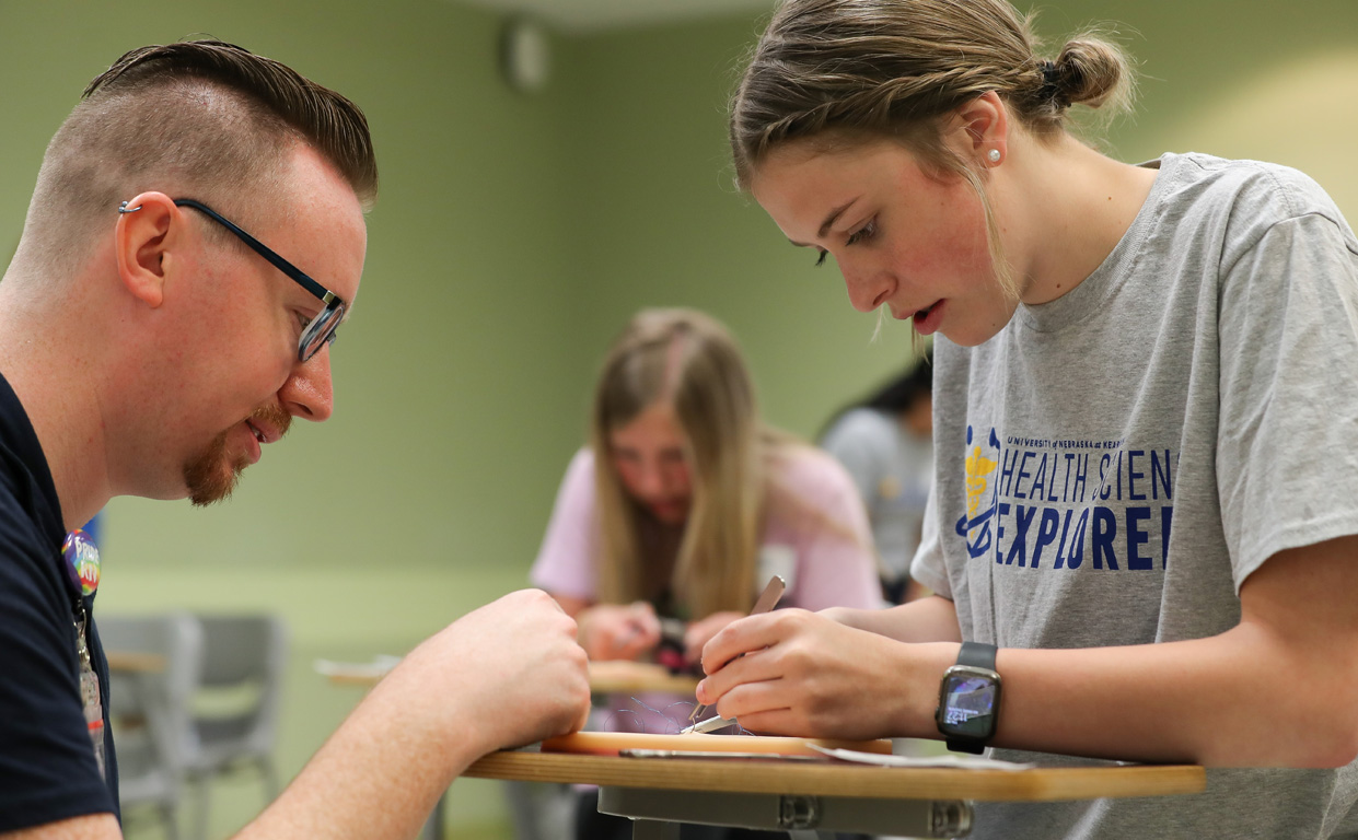 Douglass Haas, a clinical assistant professor in the UNMC College of Nursing, helps Amherst junior Sadie Ringlein with a suture activity Friday during the Health Science Explorers summer camp at UNK.