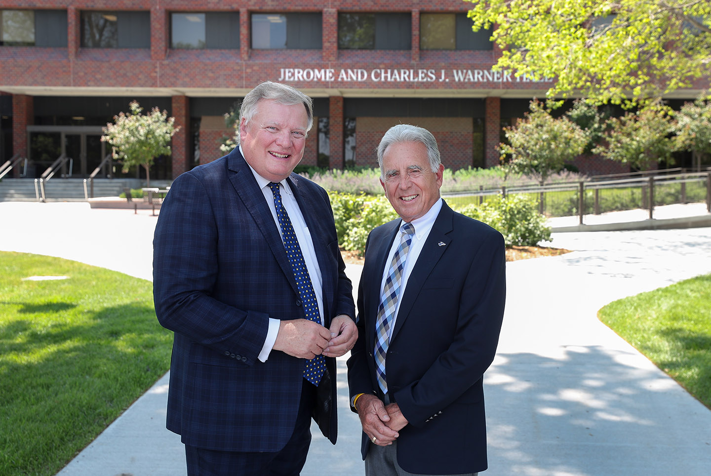 Doug Kristensen and Pete Kotsiopulos are pictured in front of Warner Hall on the UNK campus. The building is named after Charles J. Warner and his son Jerome Warner, two prominent former state senators who played a significant role in UNK’s history.