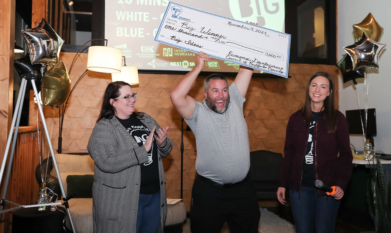 UNK senior Lance Blythe, center, celebrates with his oversized check Wednesday evening after winning the college division of the Big Idea Kearney competition.