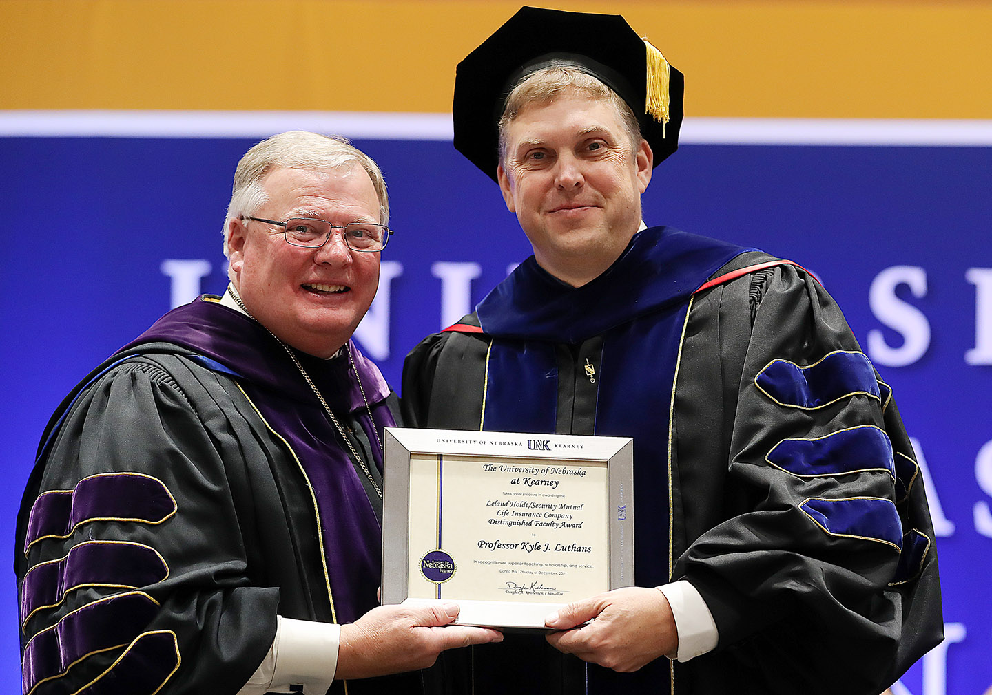 UNK Chancellor Doug Kristensen, left, presents the Leland Holdt/Security Mutual Life Distinguished Faculty Award to management professor Kyle Luthans during Friday’s winter commencement ceremony at the Health and Sports Center on campus. (Photos by Erika Pritchard, UNK Communications)
