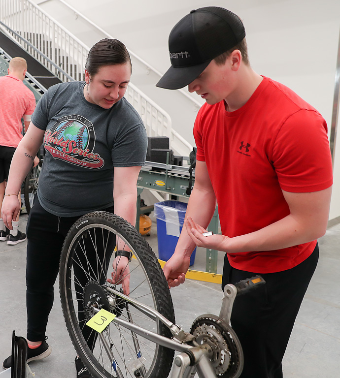UNK industrial distribution students Haleigh Hoefs, left, and Caden Runge work together to convert a standard bicycle to a motorized bike in their mechanical power class.