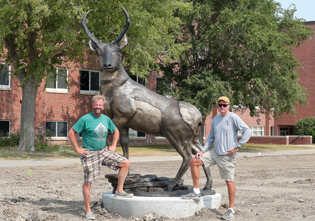 Mark Lundeen, left, and Tony Workman pose for a photo after installing the new pronghorn sculpture on campus.
