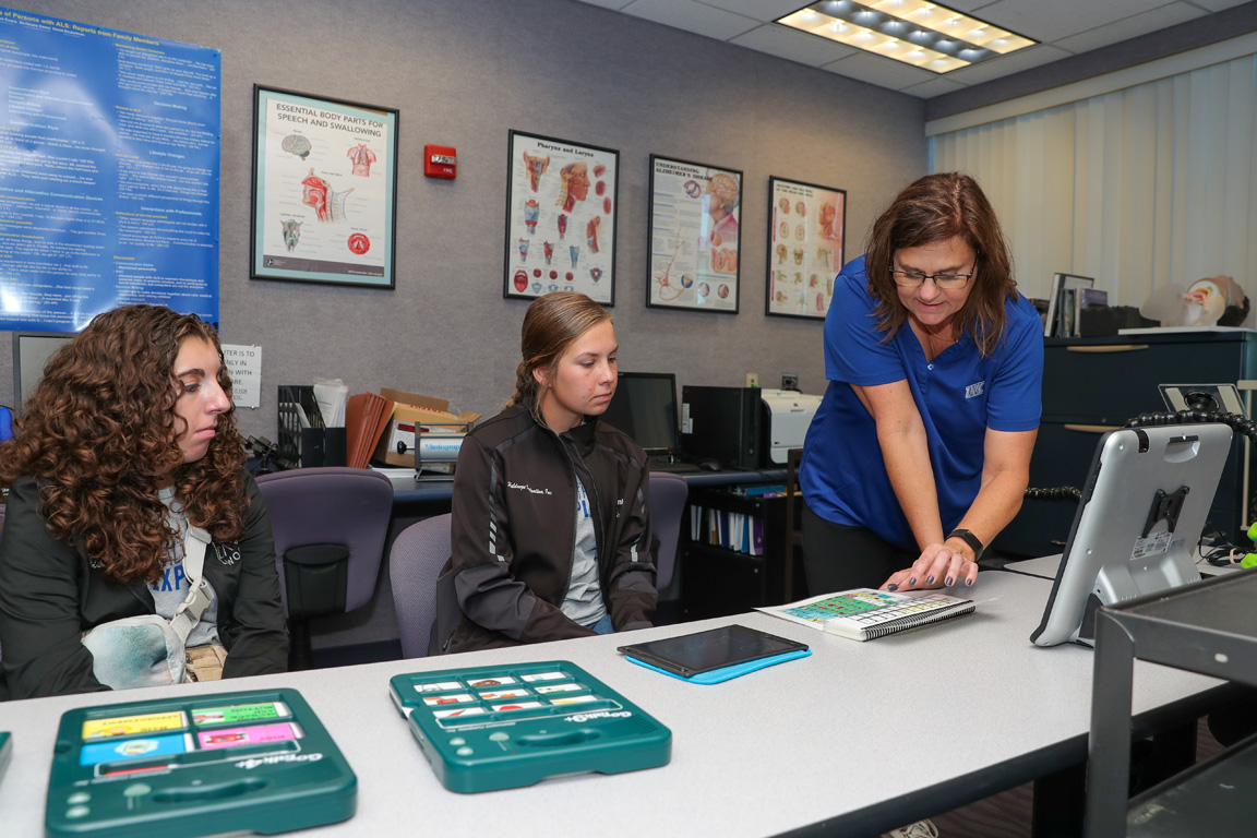 UNK professor of communication disorders Miechelle McKelvey, right, leads a session on augmentative and alternative communication during the Health Science Explorers Academy. Kearney Catholic High School junior Trista Tool, left, and Shelton High School senior Skyler Summers are among the nine students participating in the health care-focused program. (Photos by Erika Pritchard, UNK Communications)