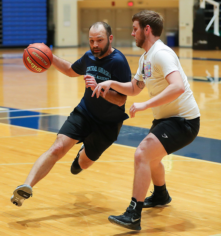 Former UNK faculty member Matt Miller tries to drive past graduate assistant Dylan Simmons during a recent noon ball game at the Health and Sports Center.