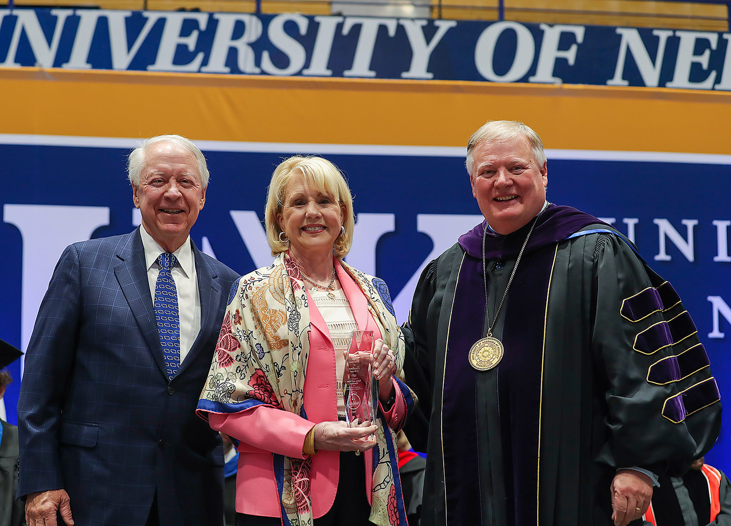 UNK Chancellor Doug Kristensen, right, presents the Ron and Carol Cope Cornerstone of Excellence Award to Brian and Carey Hamilton during Friday’s spring commencement ceremony. (Photo by Erika Pritchard, UNK Communications)