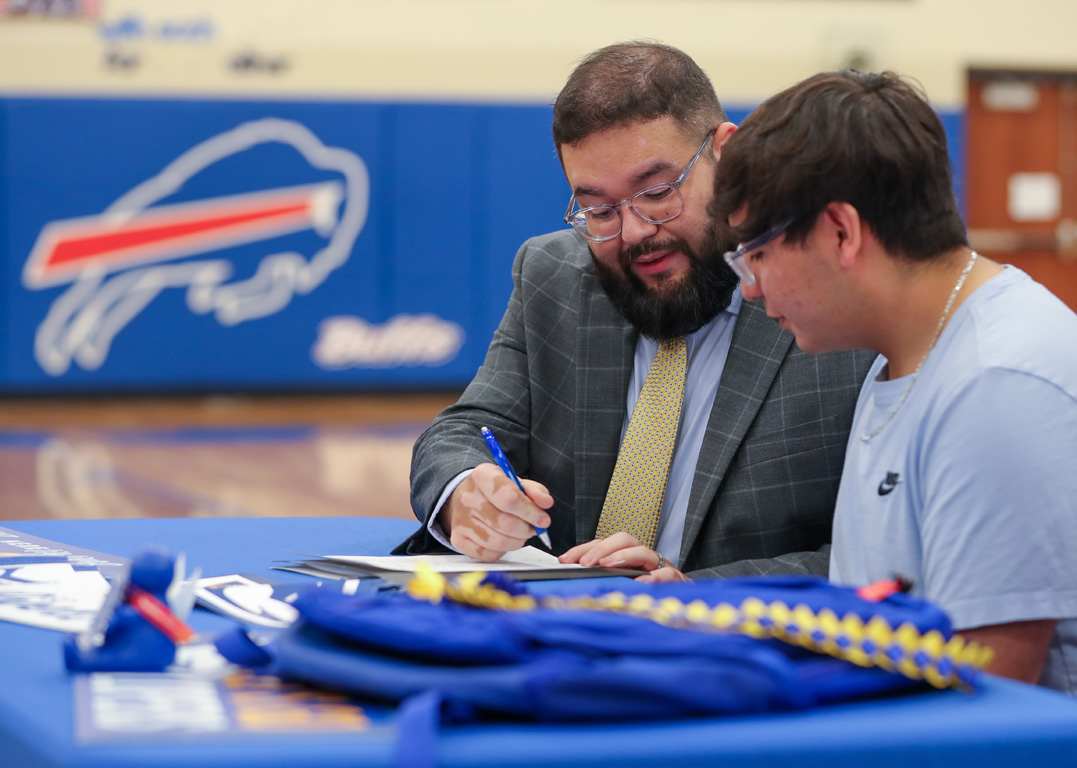 Luis Olivas, interim director of the UNK Office of Student Diversity and Inclusion, presents a scholarship to Eduardo Simental during Thursday’s signing ceremony at Gibbon Public Schools.