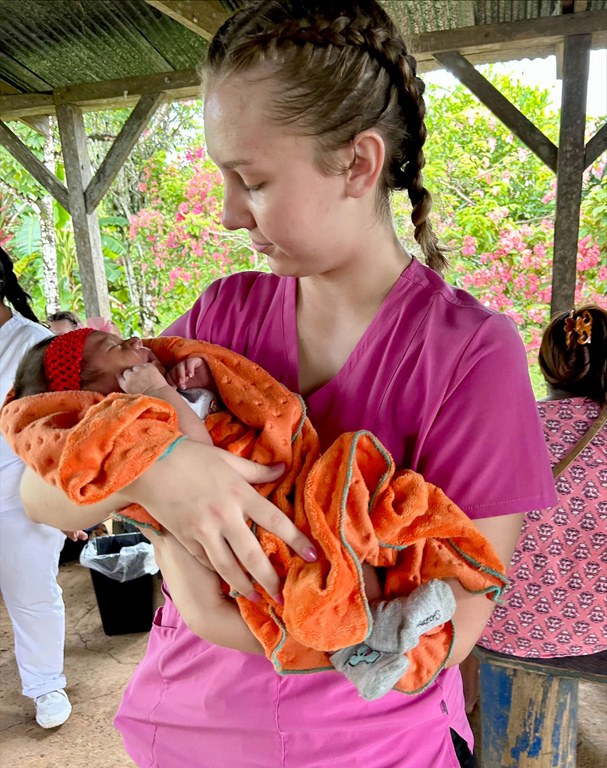 UNK student Danielle Fortik holds a baby during one of the mobile medical clinics in Bocas del Toro, Panama.