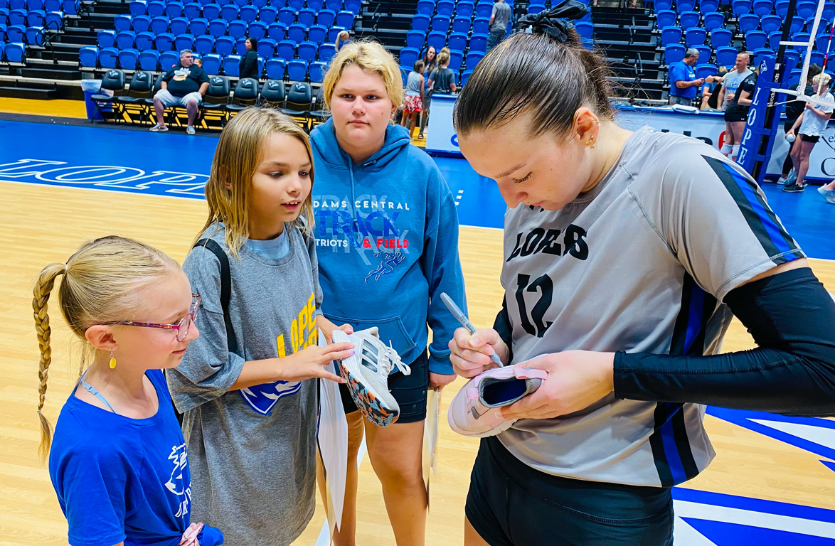 UNK volleyball player Jensen Rowse signs autographs for young fans following Wednesday night’s match at the Health and Sports Center.