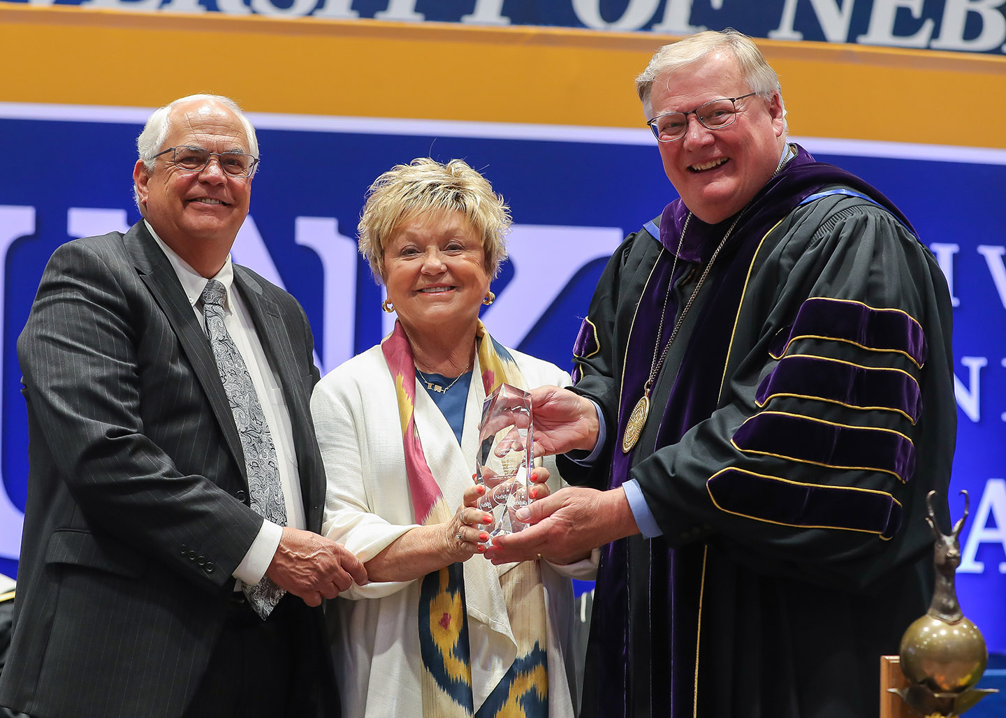 UNK Chancellor Doug Kristensen, right, presents the Ron and Carol Cope Cornerstone of Excellence Award to Tami and Jerry Hellman during Friday’s spring commencement ceremony at UNK.