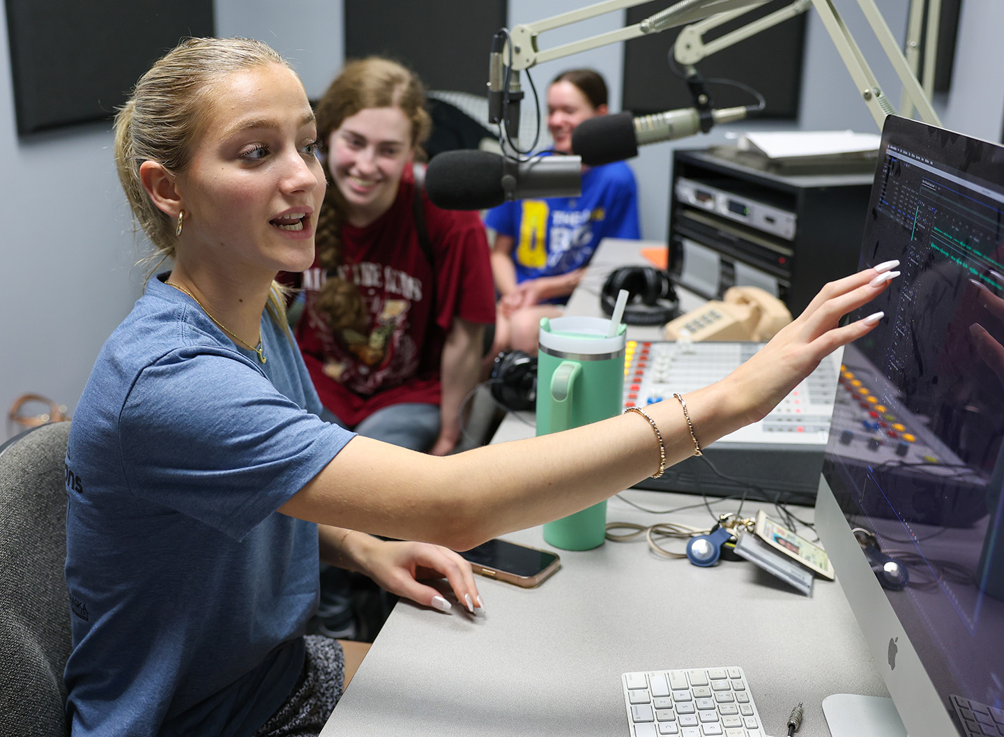 Chloe Howard of Kearney, front, gets some airtime in the UNK radio studio during the Digital Expressions Media Camp.