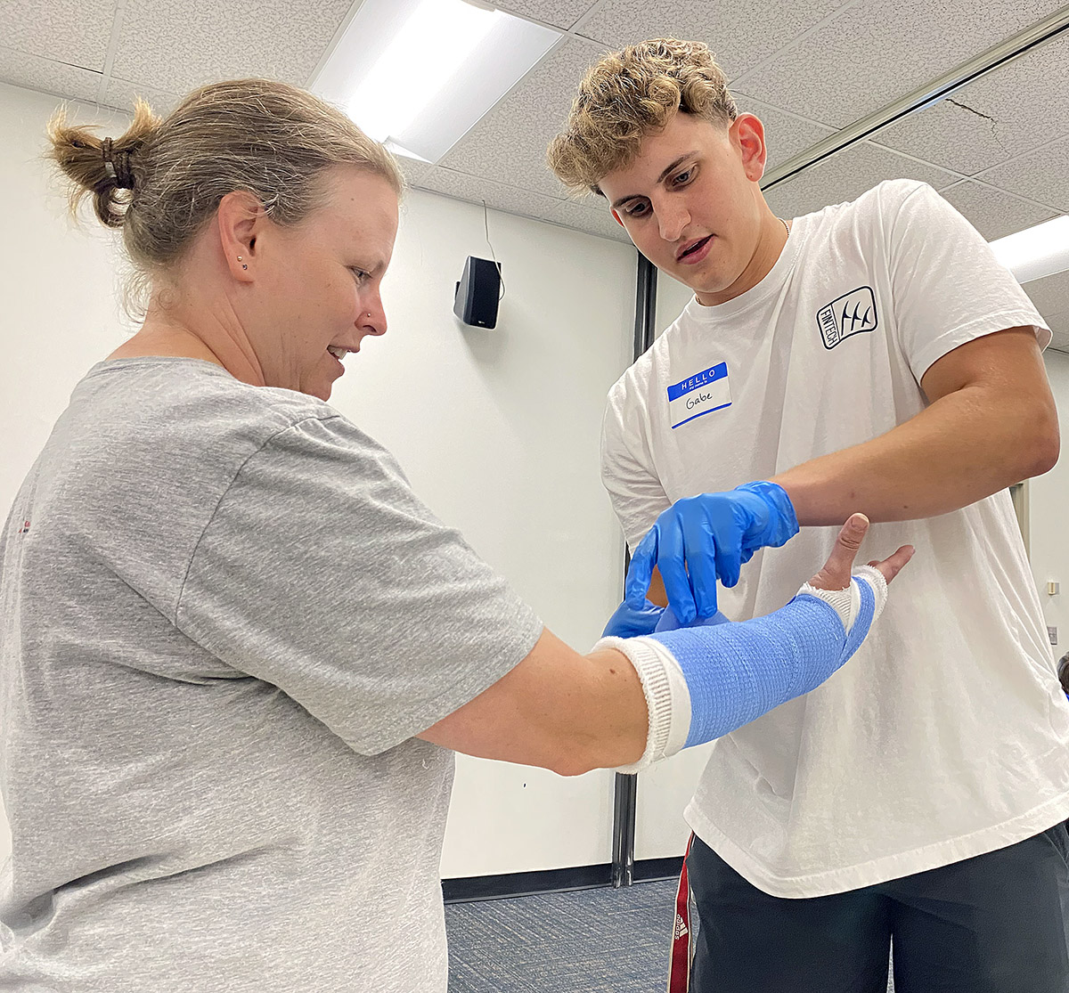 Gabe Gans of McCook applies a cast to the arm of UNK Health Sciences graduate assistant Shanon Kempt during the Health Science Explorers summer camp.