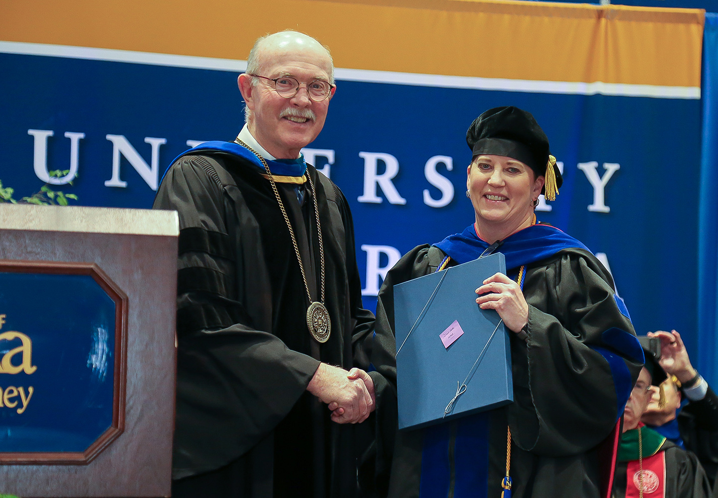 Interim Chancellor Charlie Bicak presents the Leland Holdt/Security Mutual Life Distinguished Faculty Award to UNK professor Brooke Envick during Friday’s winter commencement ceremony at the Health and Sports Center on campus. (Christine Matrangos/Ceremony Photos)