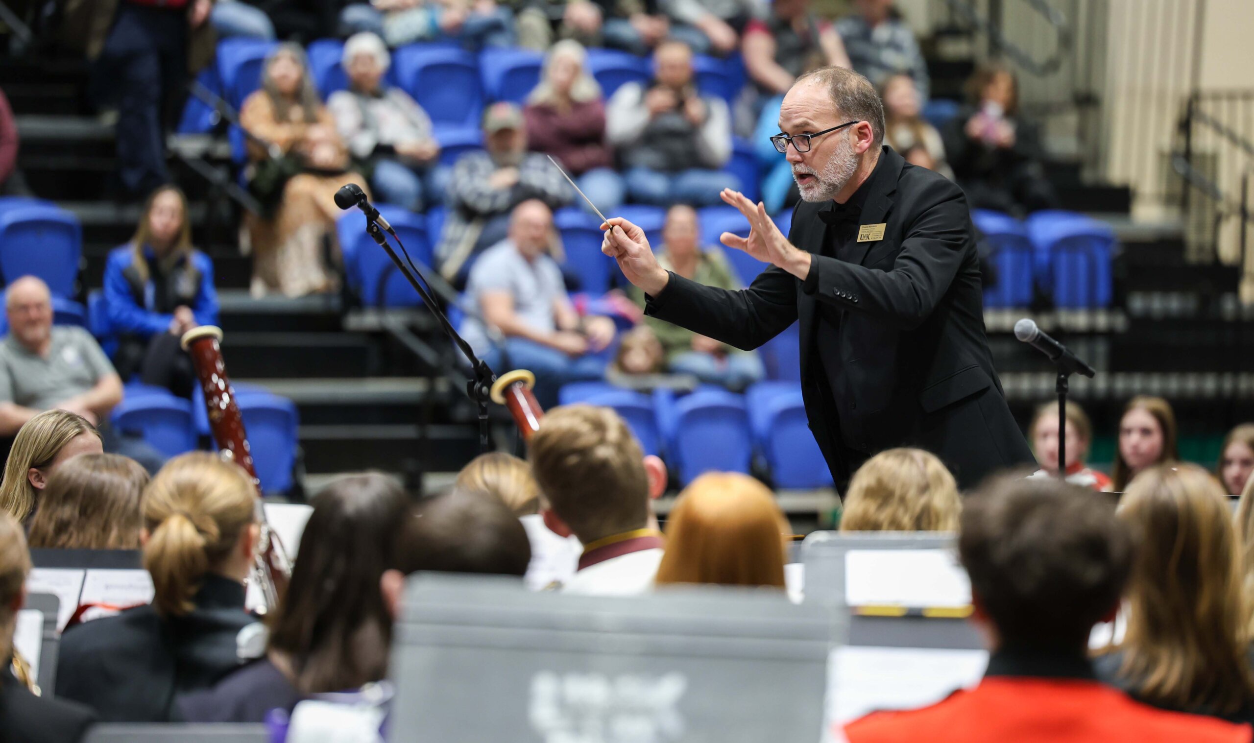 A conductor leads a band of high school students at a concert at UNK.