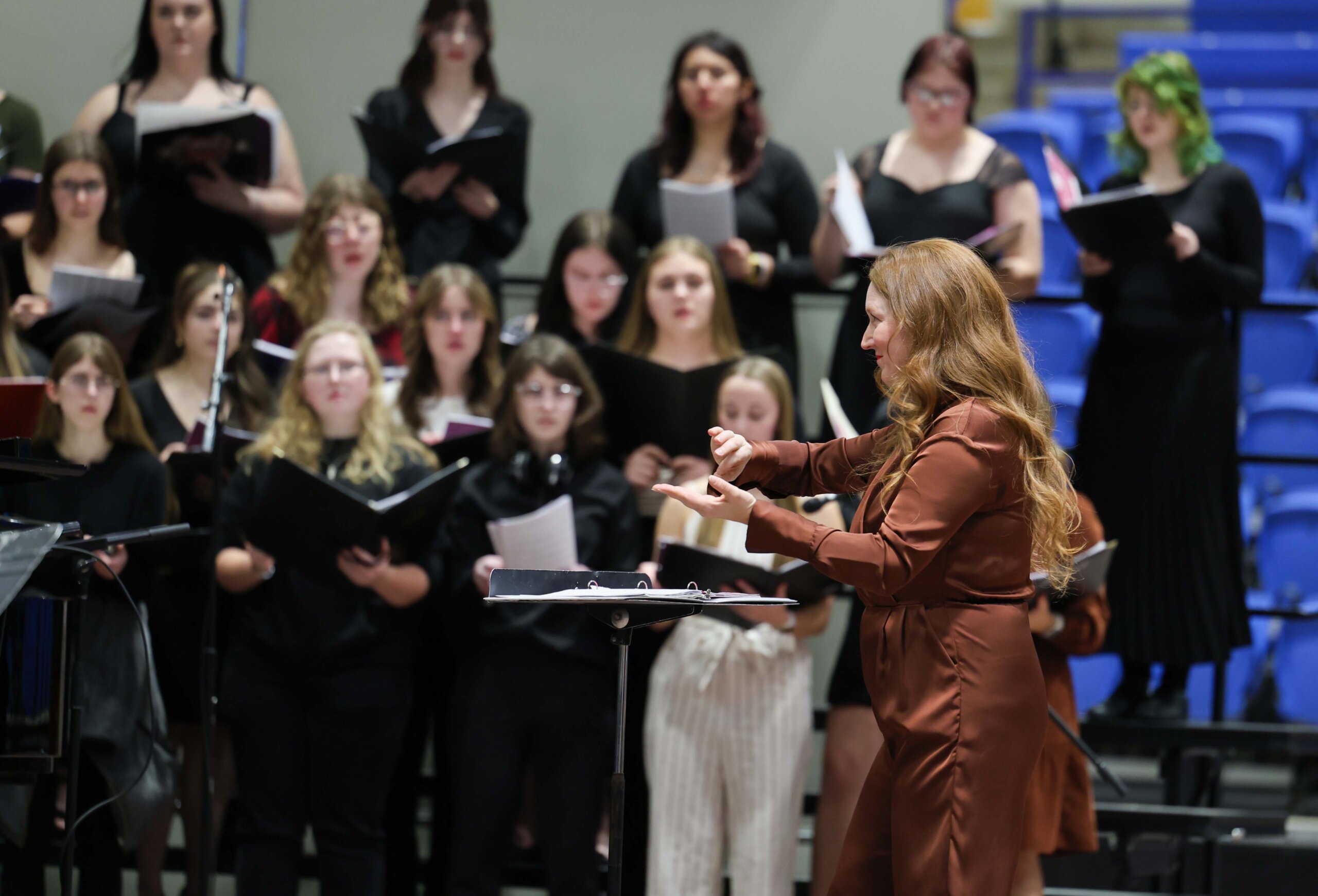 A woman conducts a choir of high school girls at a concert at UNK.