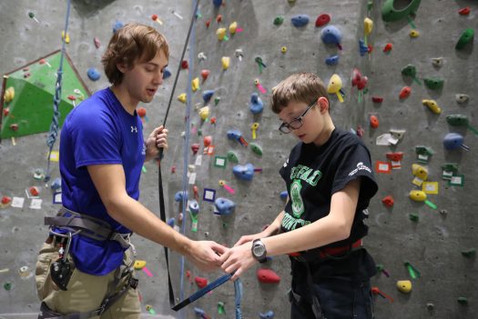 UNK student Forrest King, left, works with Pack 139 Boy Scout Grant Lewis on the rock climbing wall. Lewis is among 23 scouts developing fitness plans and working toward merit badges under the guidance of UNK students. (Photo by Corbey R. Dorsey/UNK Communications)