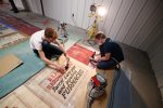 UNK students Brandon Wamberg, left, and Ned Purdy, right, work on a section of the Kearney Opera House curtain, which eventually will be displayed at Buffalo County Historical Society’s Trails & Rails Museum. (Photo by Corbey R. Dorsey, UNK Communications)