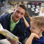UNK wrestler Mike Lambert, a senior from Fremont, reads to Meadowlark Elementary School first-grader Barrett Hill during a recent visit. Members of the UNK wrestling team stop by the Kearney elementary school each week to read with students and participate in other fun activities. (Photo by Corbey R. Dorsey, UNK Communications)