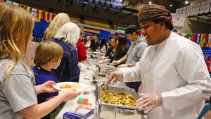Jahad Al Bulushi, a UNK student from Oman, serves chicken kabuli to a line of hungry attendees at Sunday’s Scott D. Morris International Food and Cultural Festival. Dishes from nine countries were featured during the annual event at UNK’s Health and Sports Center. (Photo by Todd Gottula, UNK Communications)
