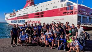 UNK wrestlers, coaches and alumni take a photo near the ferry that transported them from Athens, Greece, to Crete during last month’s international trip. (Courtesy photo)