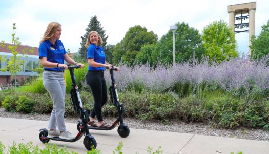 Students Rachel Higgins, left, and Courtni Heckert cruise around the University of Nebraska at Kearney campus on electric scooters. Nine scooters will be available next week for students, staff, faculty and visitors to rent and ride at UNK. (Photo by Corbey R. Dorsey, UNK Communications)