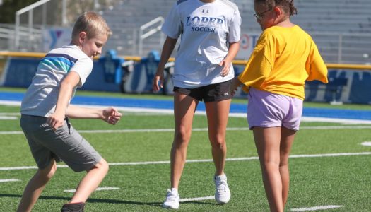 UNK soccer player Kylee Moore works with children at an activity at Cope Stadium during Early Awareness Day. Monday’s event brought 73 area fourth graders to UNK to learn more about the university, explore potential careers and have a little fun. (Photo by Corbey R. Dorsey, UNK Communications)