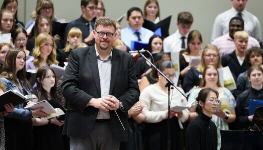 A conductor is introduced at a choral concert at UNK.